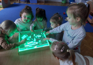 dzieci rysują obrazki na piasku w podświetlanym pojemniku