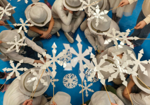 dzieci w białych kapeluszach a nad nimi białe śnieżynki