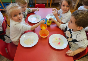 przedszkolaki malują na mleku za pomocą pipety i kolorowych barwników