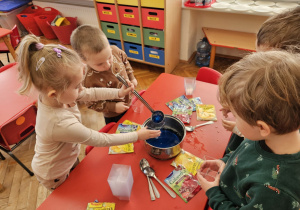 dziewczynka wlewa niebieską galaretkę do pojemnika
