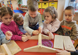 chłopiec skręca elementy karmnika z pomocą koleżanki