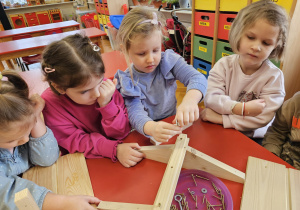 dziewczynka skręca elementy karmnika z pomocą koleżanki