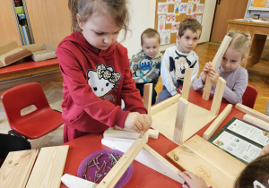 dziewczynka skręca elementy karmnika z pomocą dzieci