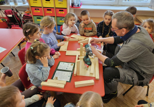 pan Krzysiu pomaga dzieciom - skręca elementy karmnika za pomocą wkrętarki