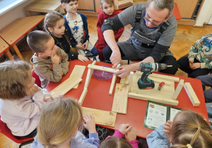 pan Krzysiu pomaga dzieciom - skręca elementy karmnika za pomocą wkrętarki
