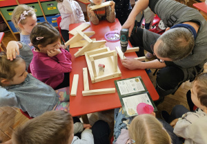 pan Krzysiu pomaga dzieciom - skręca elementy karmnika za pomocą wkrętarki