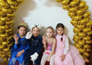 dziewczynki pozują do zdjęcia pod łukiem z balonów