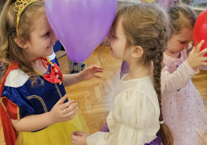 dziewczynki trzymają głowami balon tańcząc w parach