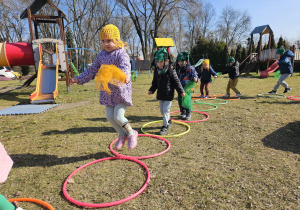 dzieci skaczą jak żabki po kolach hula hop