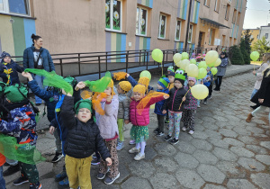 przedszkolaki z zielonymi chustkami w korowodzie przed budynkiem przedszkola