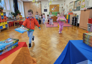 dzieci budują wieżę z książek przenosząc je jak najszybciej na stolik