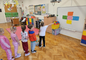 przedszkolaki rzucają piłeczką do tarczy złożonej z kolorowych karteczek z zaznaczonymi zdobytymi punktami