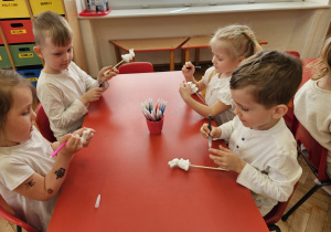 dzieci ozdabiają zajączki do dekoracji świątecznych