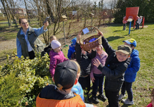 dzieci z grupy III z koszykiem znalezionym w krzewach w ogrodzie