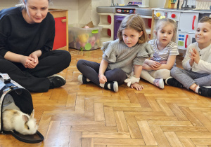 mama z króliczkiem siedzi wśród dzieci i obserwują króliczka