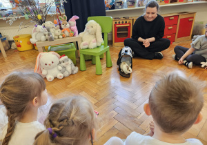 mama z króliczkiem siedzi wśród dzieci i obserwują króliczka