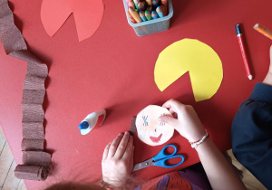 dziecko dokleja włosy do głowy lalki