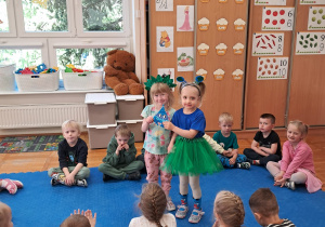 dziewczynki w strojach zielonym i niebieskim trzymają niebieską kropelkę
