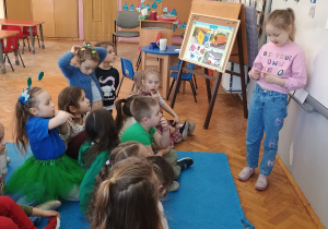 dzieci uczą się segregacji śmieci - dziewczynka dopasowuje obrazek śmieci do odpowiedniego kosza na śmieci