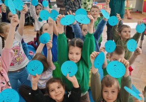 przedszkolaki pokazują emblematy wesołej i smutnej Ziemi