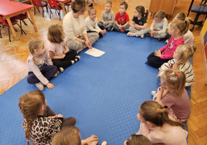 pani Kasia siedzi z dziećmi w kole i rozmawia z nimi