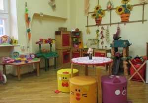 sala, kolorowy kącik do zabaw w dom z szafkami, stolikiem, pufami