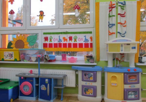 sala, kącik kuchennyz kuchenkami, firanką i wyposażeniem kuchennym